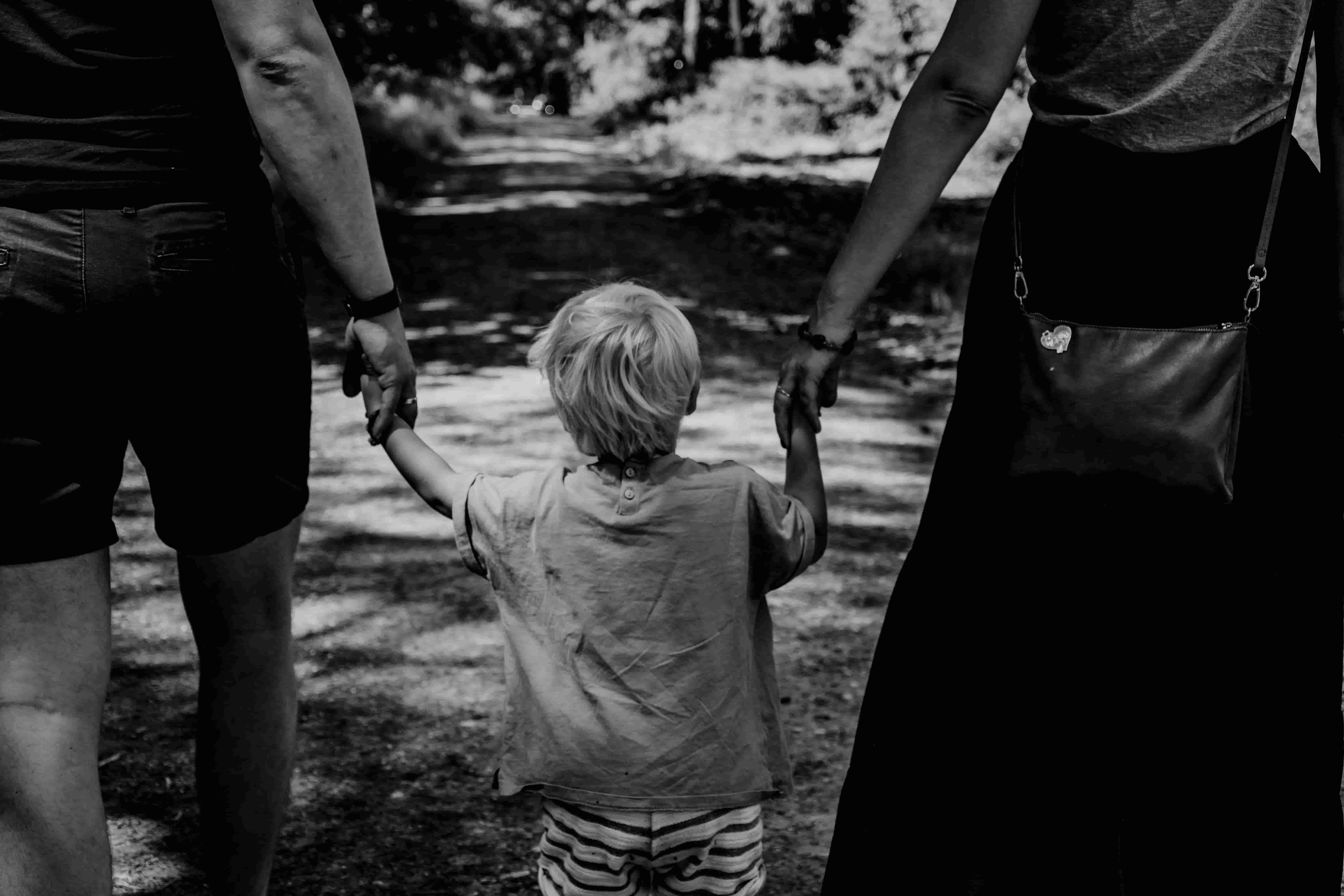 Enfant qui tient la main de ses deux parents vue de dos-unsplash